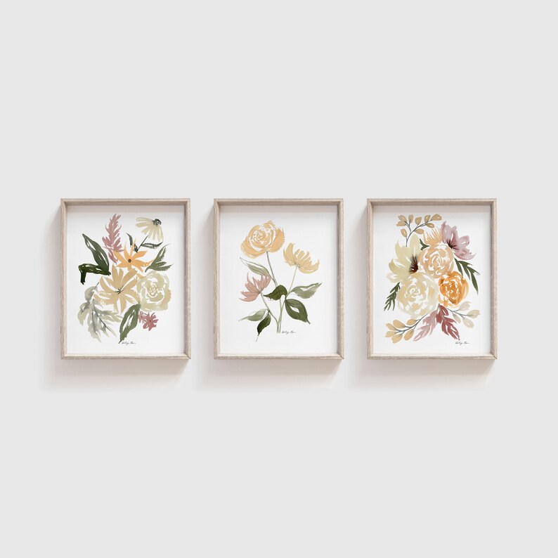 May include: Three framed watercolor paintings of floral bouquets in shades of yellow, orange, and brown. The paintings are in simple, modern frames.