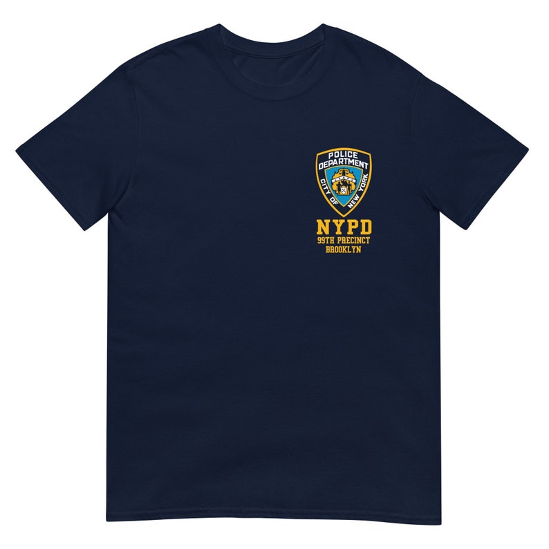 May include: Navy blue t-shirt with a yellow NYPD patch featuring the New York City Police Department logo and the text "99th Precinct Brooklyn".