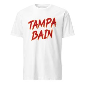 May include: White t-shirt with the text "TAMPA BAIN" in red and yellow flame-like lettering. The shirt is a short-sleeved crew neck style.