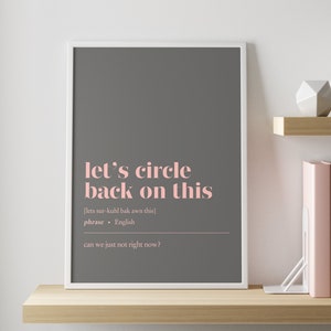 May include: A gray framed print with the text "let's circle back on this" in pink. The text is defined as a phrase in English and includes the phonetic pronunciation. The text also includes the phrase "can we just not right now?"