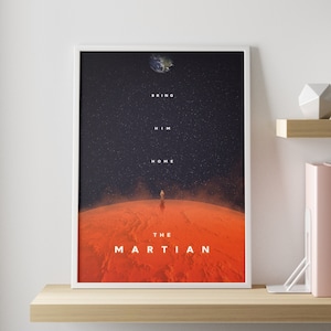 May include: A white framed poster with a black background and a red planet in the foreground. The poster features a silhouette of an astronaut standing on the planet. The text on the poster reads "Bring Him Home" and "The Martian".