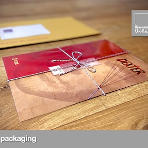 May include: A red and brown print with the word "Dexter" on it is wrapped in a clear plastic sleeve and tied with twine. The print is being packaged in a brown envelope.