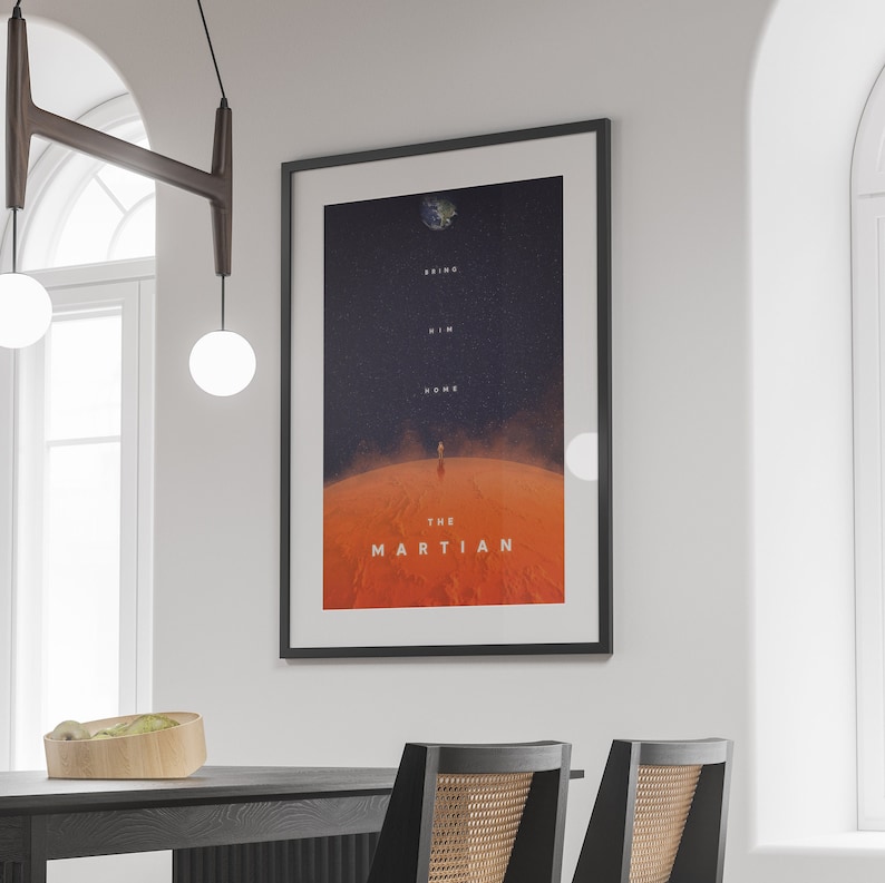 May include: A black framed poster with a red and blue image of a person walking on Mars. The poster has the text "Bring Him Home" and "The Martian" on it.