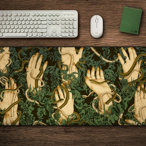 May include: A green and brown mouse mat with a pattern of hands and snakes. The hands are reaching out from a background of green leaves and vines.