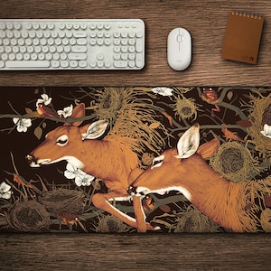 May include: A brown and tan mouse mat with a dark background featuring two deer with intricate details. The deer are surrounded by a floral design with white flowers and birds. The background also features a variety of brown and tan nests.