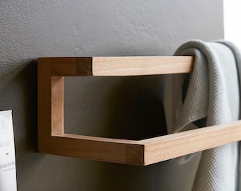 May include: A wooden towel rack with two shelves. The rack is mounted to a wall and has a towel hanging on the bottom shelf.