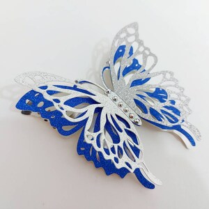 Peut inclure: Une pince &agrave; cheveux en forme de papillon avec des paillettes argent&eacute;es et bleues. Le papillon a un design d&eacute;coup&eacute; d&eacute;taill&eacute; et est accentu&eacute; de strass argent&eacute;s.