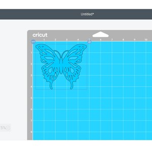 Peut inclure: Un motif de papillon bleu sur un tapis bleu clair dans le logiciel Cricut Design Space. Le motif est pr&ecirc;t &agrave; &ecirc;tre d&eacute;coup&eacute; sur une machine Cricut.