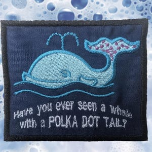 May include: Navy blue patch with a light blue whale illustration and a polka dot tail. The patch has the embroidered text: "Have you ever seen a whale with a POLKA DOT TAIL?" The patch has a black border.