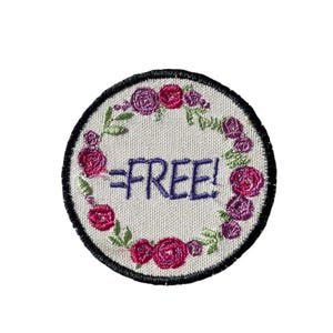May include: Embroidered patch with a white background, a black border, and the word "FREE!" in purple. The patch is decorated with a floral wreath of pink and purple roses and green leaves.