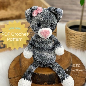 May include: A handmade crochet cat doll in shades of gray and white, with a pink bow and nose. The doll has black eyes and is sitting on a wooden surface. Text on the image reads "LOW SEW PDF Crochet Pattern".