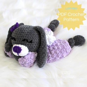 May include: A handmade crochet bunny in shades of gray and lavender, with a white and purple face. The bunny has closed eyes and a small purple bow. The text "LOW SEW PDF Crochet Pattern" is in the upper right corner.