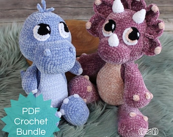 Puede incluir: Paquete de patrones de crochet PDF con dos juguetes de dinosaurio amigurumi. Un dinosaurio azul y un triceratops morado con cuernos blancos. Ambos juguetes tienen ojos grandes y están sentados sobre una superficie verde peluda.