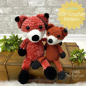 Peut inclure: Un patron de crochet pour réaliser deux peluches de renard. Le patron est disponible en téléchargement PDF. Le plus grand renard est rouge et le plus petit est orange. Les deux renards ont des yeux et des nez noirs et des museaux blancs.