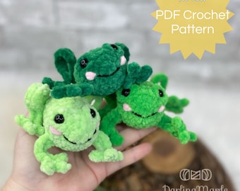 May include: Three green crocheted frog plushies with black eyes and pink smiles. The plushies are stacked on top of each other and are being held in a hand. The image includes the text "NO SEW PDF Crochet Pattern".