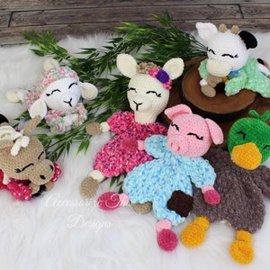 May include: Six crocheted stuffed animals, including a lamb, a llama, a pig, a cow, a duck, and a horse. The animals are all wearing different colored clothes and have embroidered eyes and mouths.