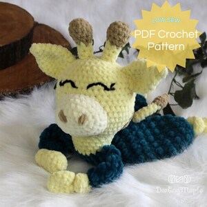 May include: A handmade crochet giraffe toy in yellow, cream, and teal. The giraffe has a smiling face with black embroidered details and brown horns. The image includes text that says "LOW SEW PDF Crochet Pattern".
