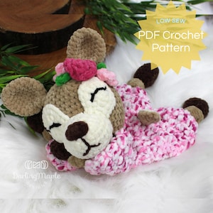 May include: A crochet pattern for a sleeping fawn with a pink and white floral dress. The pattern is available as a PDF download and is labeled "Low Sew PDF Crochet Pattern".