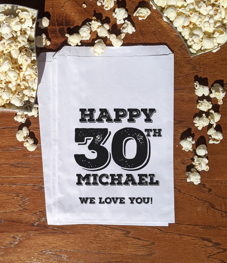 Może przedstawiać: Biała papierowa torba z czarnym tekstem, kt&oacute;ry brzmi "Happy 30th Michael We Love You!"