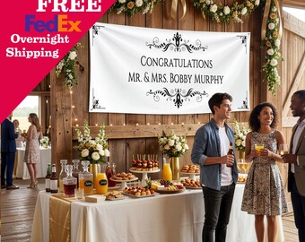 May include: A white rectangular banner featuring black decorative scrollwork corners and center flourishes, with the text CONGRATULATIONS MR. & MRS. BOBBY MURPHY printed in a black serif font, displayed horizontally against a wooden wall.