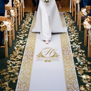 May include: White aisle runner with gold floral designs and the couple's names, "Kelly and Janelle", and a monogram "H" in a circle.