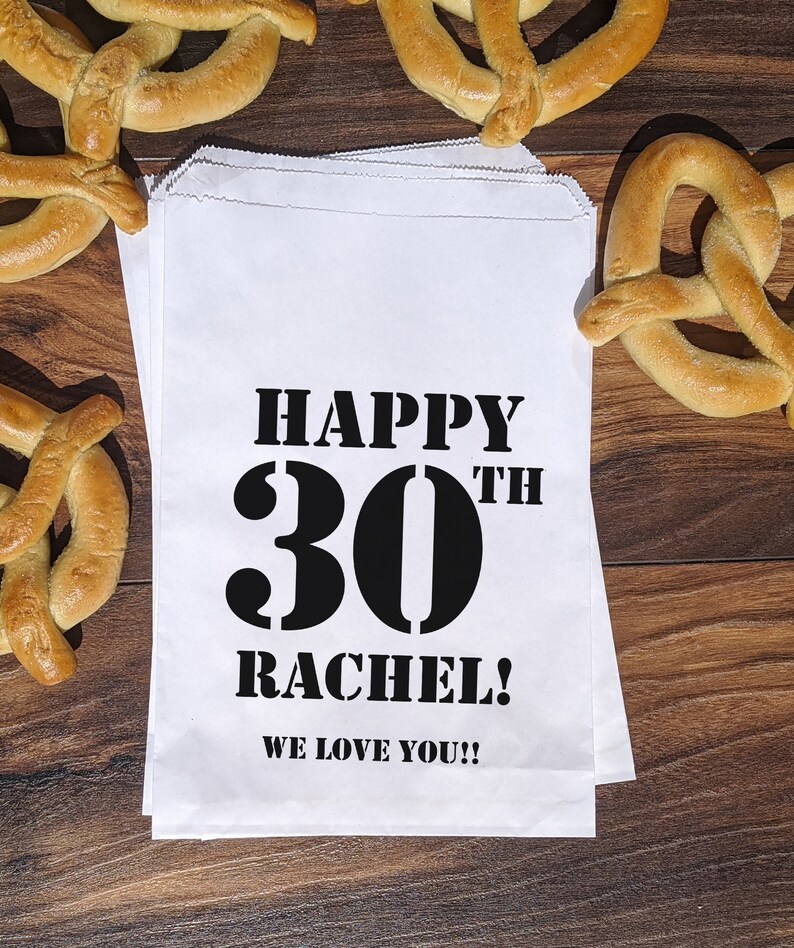 Może przedstawiać: Biała papierowa torba prezentowa z czarnym tekstem, kt&oacute;ry brzmi "Happy 30th Rachel! We love you!!"