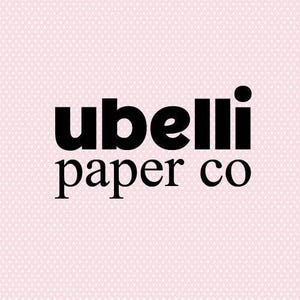 Op de afbeelding: Het logo van Ubelli Paper Co. in vette, zwarte letters tegen een lichtroze achtergrond met een subtiel wit stippenpatroon. De woorden 'ubelli' en 'paper co' zijn gestapeld.