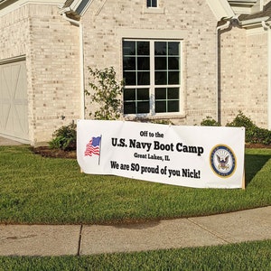Peut inclure: Une banni&egrave;re blanche sur une pelouse indique : "Off to the U.S. Navy Boot Camp, Great Lakes, IL. We are SO proud of you Nick !" Un drapeau am&eacute;ricain et l'embl&egrave;me de la marine sont &eacute;galement affich&eacute;s. La banni&egrave;re est devant une maison.
