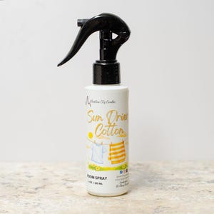 May include: A white room spray bottle with a black spray nozzle. The label reads "Sun Dried Cotton" with a graphic of laundry on a clothesline. The bottle contains 4 oz / 120 mL of room spray.