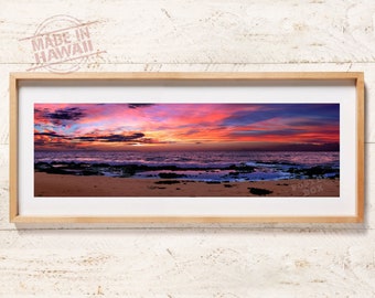 May include: A panoramic photograph of a sunset over the ocean. The sky is a vibrant mix of pink, orange, and purple hues, with clouds reflecting the colors. The ocean is a deep blue, with waves crashing on the sandy shore.