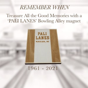 May include: A white wooden magnet with brown wood grain accents. The magnet features the text "PALI LANES" in brown lettering with the text "KAILUA, HI" below. The magnet is a reminder of the bowling alley that was open from 1961 to 2021.