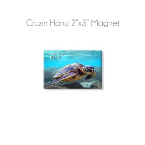 May include: A 2" x 3" magnet featuring a green sea turtle swimming underwater. The turtle is in focus, with the blue water and coral reef in the background. The text "Cruzin Honu Hawaii" is printed in the top left corner of the magnet.