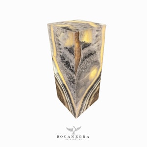 May include: A tall, rectangular block of onyx with a unique, swirling pattern of black, white, and yellow. The onyx is illuminated from within, highlighting the intricate details of the stone.