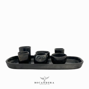 May include: A set of six black onyx cups and a matching oval tray. The cups are of various shapes and sizes, and the tray has a smooth, polished surface.