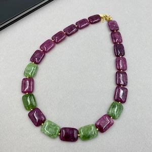 May include: A necklace featuring alternating rectangular beads in shades of deep red and light green. The beads are strung together with gold-colored connectors, creating a vibrant and eye-catching accessory.