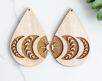 May include: A pair of wooden teardrop-shaped earrings with a carved design of three crescent moons and a sun with a floral pattern.