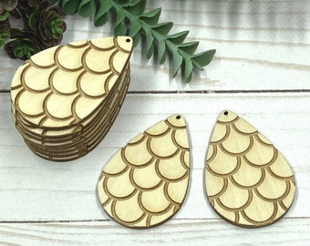 May include: Two unfinished wooden teardrop-shaped earring blanks with a mermaid scale pattern. The blanks are stacked on top of each other.