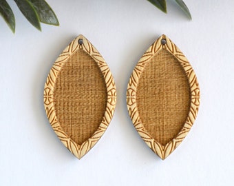 May include: Two wooden leaf-shaped earring blanks with a carved design around the edge. The blanks are unfinished and ready to be decorated.