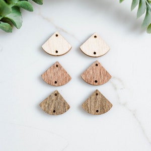 May include: Six wooden earring blanks in three different shades of brown. The blanks are shaped like a half-circle with a pointed tip. Each blank has two holes for attaching earring findings.