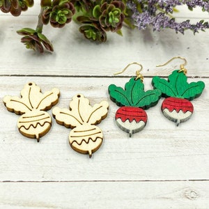 May include: Four wooden earrings shaped like radishes. Two are painted with green tops and red bodies, and two are natural wood.