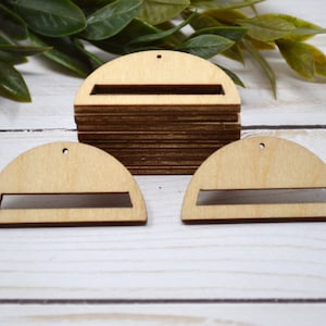 May include: Three unfinished wooden half-circle shapes with a rectangular cutout in the center. The shapes have a hole at the top for hanging.