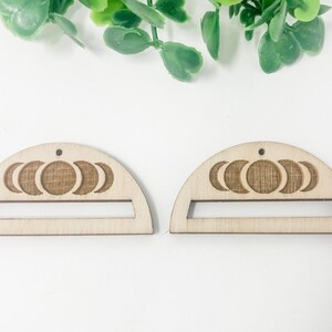 May include: Two unfinished wooden half-moon shapes with a cutout in the center and a moon phase design.
