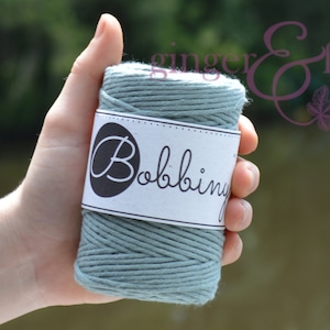 May include: A roll of light blue cotton twine with a white label that says "Bobbiny".