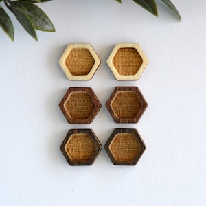 May include: Six wooden hexagon-shaped earring blanks with a light brown wood center and a dark brown wood outer edge.