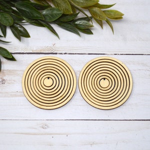 May include: Two wooden circles with concentric rings, each with a smaller circle in the center. The circles are light brown and have a smooth, polished finish.
