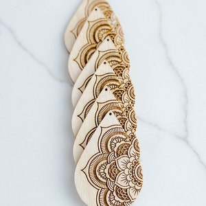May include: Five unfinished wooden teardrop-shaped earrings with intricate laser-cut mandala designs.