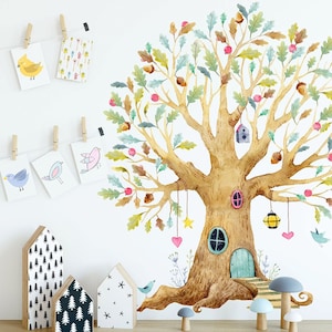 Op de afbeelding: Een aquarel-illustratie van een boom met een huis in de stam. De boom heeft een bruine stam, groene bladeren en roze bloemen. Het huis heeft een blauwe deur en een raam. Er hangen vogels en sterren aan de takken.