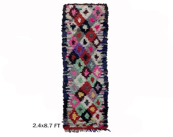 May include: A long, narrow, colorful rug with a geometric pattern. The rug is made of wool and has a fringe on the ends. It measures 2.4 x 8.7 feet.