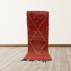 May include: A red and orange runner rug with a geometric pattern. The rug has a fringe on the bottom edge.