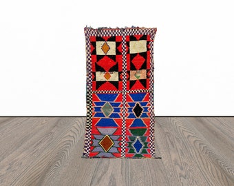 May include: A colorful Moroccan rug with geometric patterns in shades of red, blue, green, and yellow. The rug has a fringed edge and is made of wool.